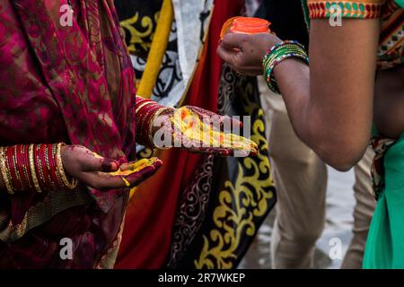 Les dévotés peignent leurs paumes avec de la poudre colorée pendant Chhath Puja à Varanasi, Inde Banque D'Images