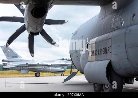 Un F-16 polonais Fighting Falcon passe devant un américain Force aérienne C-130 Hercules, affecté à la 153rd Escadre de transport aérien, Garde nationale du Wyoming, lors de l'exercice Air Defender 2023 (AD23) à la base aérienne de Krzesiny, en Pologne (15 juin 2023). L'exercice AD23 intègre la puissance aérienne américaine et alliée pour défendre des valeurs communes, tout en tirant parti et en renforçant des partenariats essentiels pour décourager l'agression dans le monde entier. (É.-U. Photo de la Garde nationale aérienne par le sergent d'état-major Paul Helmig) Banque D'Images