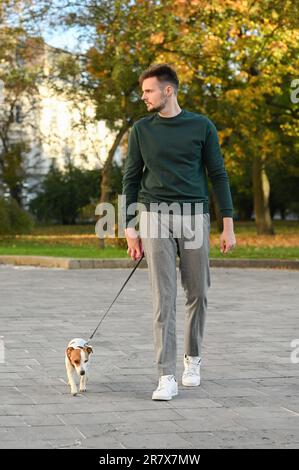 Homme avec l'adorable Jack Russell Terrier dans la rue de la ville. Chien marchant Banque D'Images