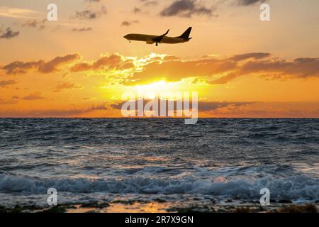 Vol en avion au-dessus de la mer au coucher du soleil. Le soleil brille à travers les nuages Banque D'Images