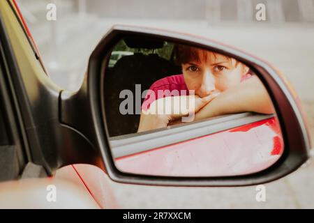 Jolie femme dans la fenêtre de voiture. Fille souriante dans le miroir de voiture. Concept de voyage. Concept de voyage joyeux. Concept de circulation urbaine. Conduite automatique. Fille posant en voiture Banque D'Images