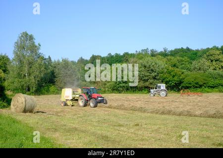 les tracteurs assemblent et retournent des lignes d'herbe coupée, puis se sont mis en balles dans le comté de zala en hongrie Banque D'Images