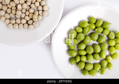 Pois frais et séchés sur une assiette avec une plaque de fond sur fond blanc Banque D'Images