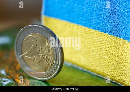 Pièce de 2 euros sur fond de concept de drapeau ukrainien, coopération commerciale de l'Union européenne avec l'Ukraine, différents systèmes monétaires, relat des affaires Banque D'Images