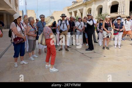 Le guide s'arrête de voyage de groupe à l'ombre pour lui donner les explications rituelles sur la ville de la Valette, Malte Banque D'Images