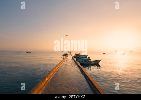 Lever de soleil sur l'horizon de la mer. Long quai avec bateaux amarrés dans le village de pêcheurs de l'île de Phu Quoc, Vietnam Banque D'Images