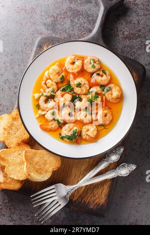 Crevettes frites à l'ail et poivrons chauds dans de l'huile d'olive parfumée en gros plan sur une planche de bois sur la table. Vue verticale du dessus Banque D'Images