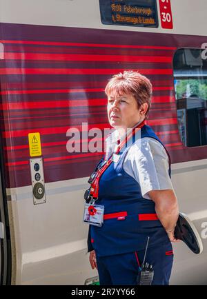 Gare de Grantham – Une femme chef d'orchestre ou garde qui expédie un train Azuma du nord-est (LNER) de Londres depuis la plate-forme Banque D'Images