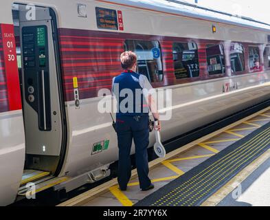 Gare de Grantham – Une femme chef d'orchestre ou garde qui expédie un train Azuma du nord-est (LNER) de Londres depuis la plate-forme Banque D'Images