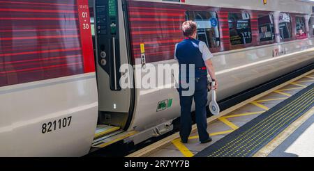 Gare de Grantham – Une femme chef d'orchestre ou garde qui expédie un train Azuma du nord-est (LNER) de Londres depuis la plate-forme Banque D'Images