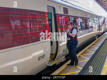 Gare de Grantham – Une femme chef d'orchestre ou garde qui expédie un train Azuma du nord-est (LNER) de Londres depuis la plate-forme Banque D'Images