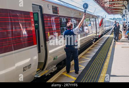 Gare de Grantham – Une femme chef d'orchestre ou garde qui expédie un train Azuma du nord-est (LNER) de Londres depuis la plate-forme Banque D'Images