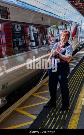 Gare de Grantham – Une femme chef d'orchestre ou garde qui expédie un train Azuma du nord-est (LNER) de Londres depuis la plate-forme Banque D'Images