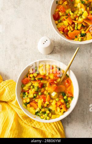 Soupe minestrone de courgettes et tomates, oignons et carottes, maïs et pois avec persil, vue de dessus des assiettes à soupe, soupe végétarienne Banque D'Images