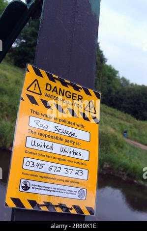 Manchester, Royaume-Uni, 18th juin 2023. Un avis de protestation de la campagne de dirtywater sur le pont de Jackson au-dessus de la rivière Mersey allègue que la rivière Mersey, dans le parc aquatique de sale, au Royaume-Uni, est polluée par des eaux usées brutes et allègue que United Utilities (UU) est responsable et donne un numéro de téléphone pour enregistrer une plainte. La campagne de l'eau sale semble faire partie de la rébellion de l'extinction. En février, la BBC a rapporté que le conseil Stockport voisin a lancé une enquête après avoir constaté que l'UU avait mis des déchets dans la rivière Mersey 977 fois en 2022. Crédit : Terry Waller/Alay Live News Banque D'Images