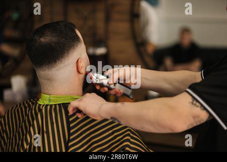 le coiffeur professionnel rasse les poils de l'homme au salon de coiffure. Vue arrière du client Banque D'Images