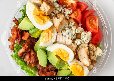 Salade cobb saine dans un emballage en plastique pour emporter ou livraison de nourriture sur fond blanc. vue de dessus. régime de céto Banque D'Images