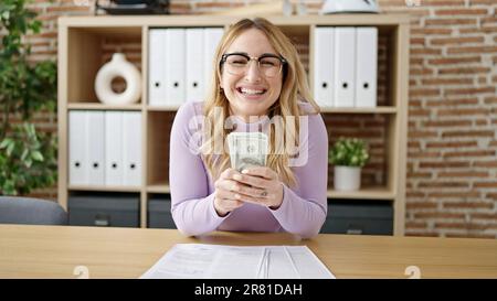 Jeune belle femme hispanique d'affaires femme tenant des dollars au bureau Banque D'Images