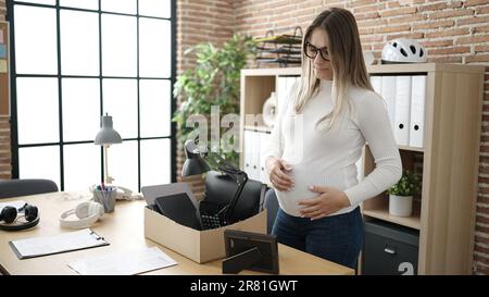 Une jeune femme enceinte a été tirée pour emballer ses effets depuis son lieu de travail en touchant le ventre au bureau Banque D'Images