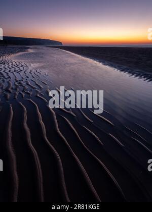 Nature's Brushstroke : un lever de soleil matinal envoûtant peint des ondulations délicates dans le sable de Culver Cliff, île de Wight Banque D'Images