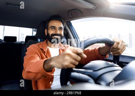 Joyeux homme du Moyen-Orient assis dans le véhicule, conduisant une nouvelle voiture Banque D'Images