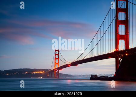 Une vue spectaculaire sur le Golden Gate Bridge, illuminé dans le ciel nocturne, se reflète dans les eaux calmes en contrebas Banque D'Images