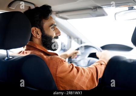 Indian Man Driving car regardant de côté, vue depuis le siège arrière Banque D'Images