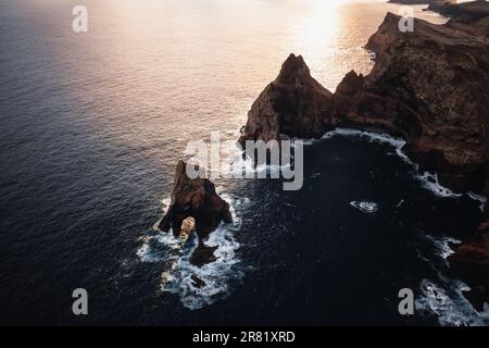 Une scène tranquille d'une étendue d'eau, bordée de rochers déchiquetés, qui s'enclame contre le rivage de l'océan bleu profond Banque D'Images