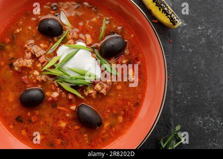 Soupe ukrainienne solyanka à la viande, aux olives, à la crème aigre, aux herbes et au citron Banque D'Images