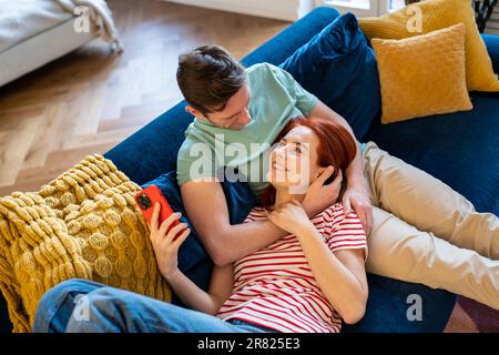 Jeune couple homme et femme se reposant sur un canapé, profitant de la vie mariée Banque D'Images