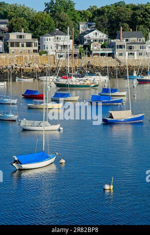 Les voiliers amarrés dans le port de Rockport avec une rangée de maisons bordant des rives bordées de pierre Banque D'Images