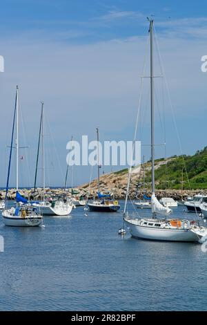 Les voiliers amarrés dans le canal du port de Rockport, bordés de jetée en pierre et d'affleurement rocheux Banque D'Images