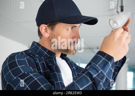 homme changeant d'ampoule dans le projecteur Banque D'Images