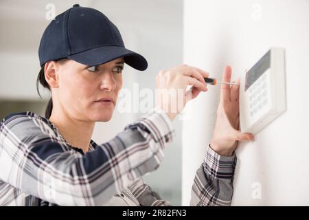 une femme travaillant sur le thermostat Banque D'Images