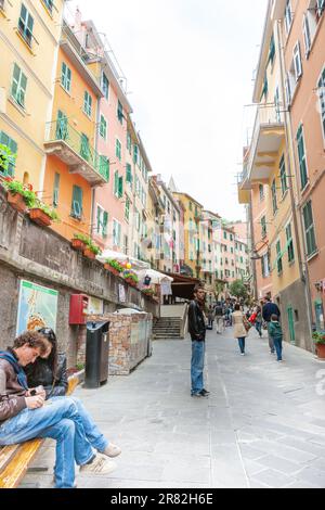 Riomaggiore Italie - 24 avril 2011 ; vue le long de la rue typique de la ville étroite avec des touristes et de hauts murs d'immeubles d'appartements. Banque D'Images