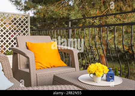 Coussin orange et fleurs de chrysanthème jaune sur meubles de jardin en rotin à l'extérieur Banque D'Images