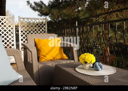 Coussin orange et fleurs de chrysanthème jaune sur meubles de jardin en rotin à l'extérieur Banque D'Images