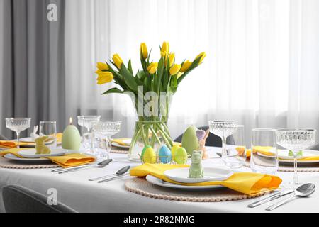 Table festive avec verres, œufs peints et vase de tulipes. Fête de Pâques Banque D'Images