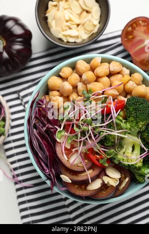 Délicieux bol végétalien avec brocoli, chou rouge et pois chiches sur table blanche, plat Banque D'Images