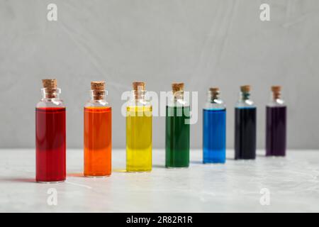 Bouteilles en verre avec différentes couleurs alimentaires sur table en marbre gris clair Banque D'Images