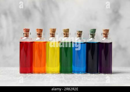 Flacons en verre avec différentes couleurs alimentaires sur table blanche Banque D'Images