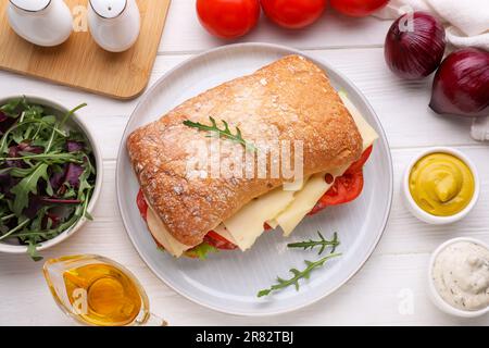 Délicieux sandwich avec une garniture savoureuse et des ingrédients sur une table en bois blanc, plat Banque D'Images
