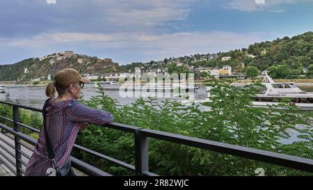 Femme touriste montres bateau de croisière et barge fluviale sur le Rhin à Coblence, Allemagne. La forteresse d'Ehrenbretistein est en arrière-plan haut sur la colline. Banque D'Images