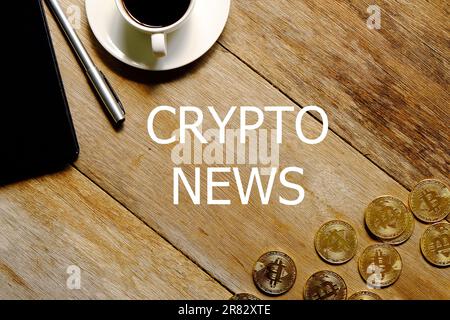Vue de dessus d'une tasse de café, réplique de bitcoin doré, bloc-notes et stylo sur fond de bois écrit avec CRYPTO NEWS. Banque D'Images