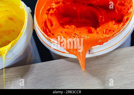 La peinture orange s'égoutte du corps blanc. l'encre plastisol est utilisée pour l'impression sur des tissus car elle est durable, facile à durcie et peut être étirée sans effort Banque D'Images