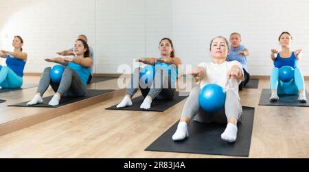 Femme âgée qui fait des sit-ups avec le ballon pendant l'entraînement de pilates Banque D'Images