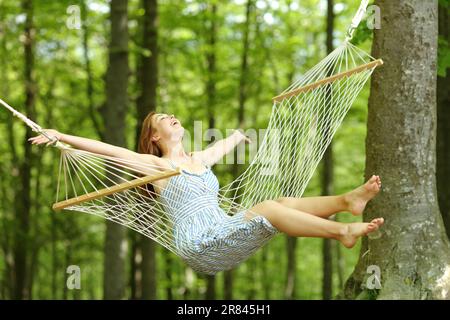 Une femme heureuse se balançant sur un hamac au printemps dans une forêt Banque D'Images