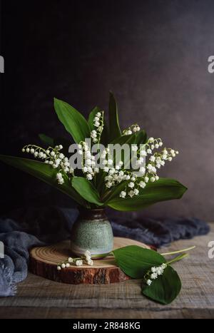 Encore la vie de petit vase de lis de la vallée fleurs sur table en bois. Banque D'Images