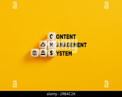 L'acronyme CMS et Content Management System text sur cubes en bois sur fond jaune. Banque D'Images