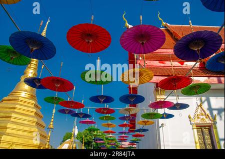 Parasols aux couleurs vives suspendus pour la décoration à l'entrée d'un temple en Thaïlande Banque D'Images